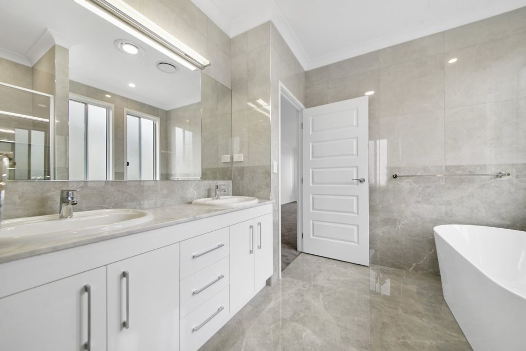 Modern bathroom interior with double vanity and freestanding bathtub.